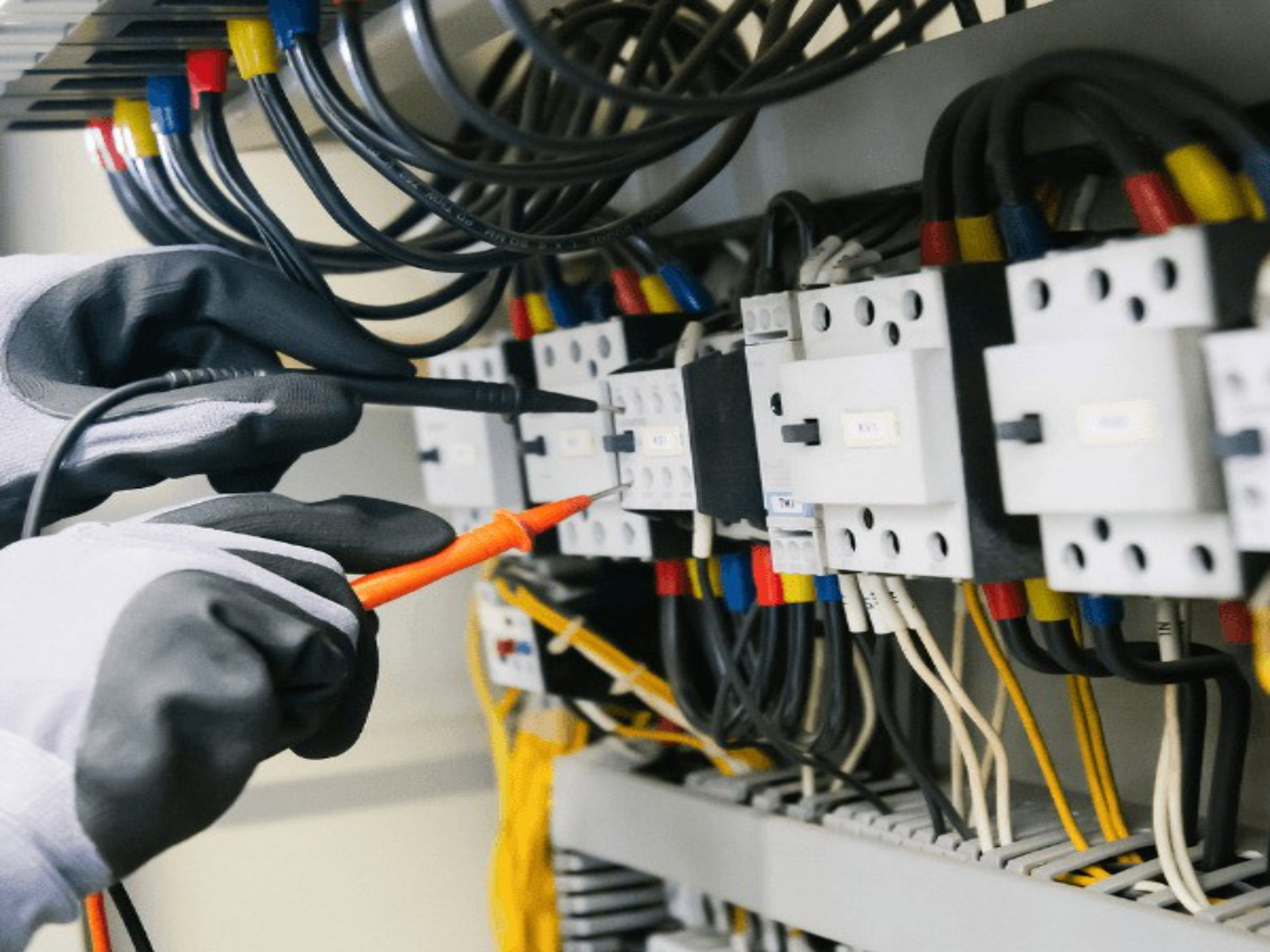 Electrician testing an electrical control panel with multimeter probes